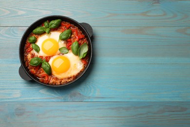 Delicious Shakshuka on light blue wooden table, top view. Space for text