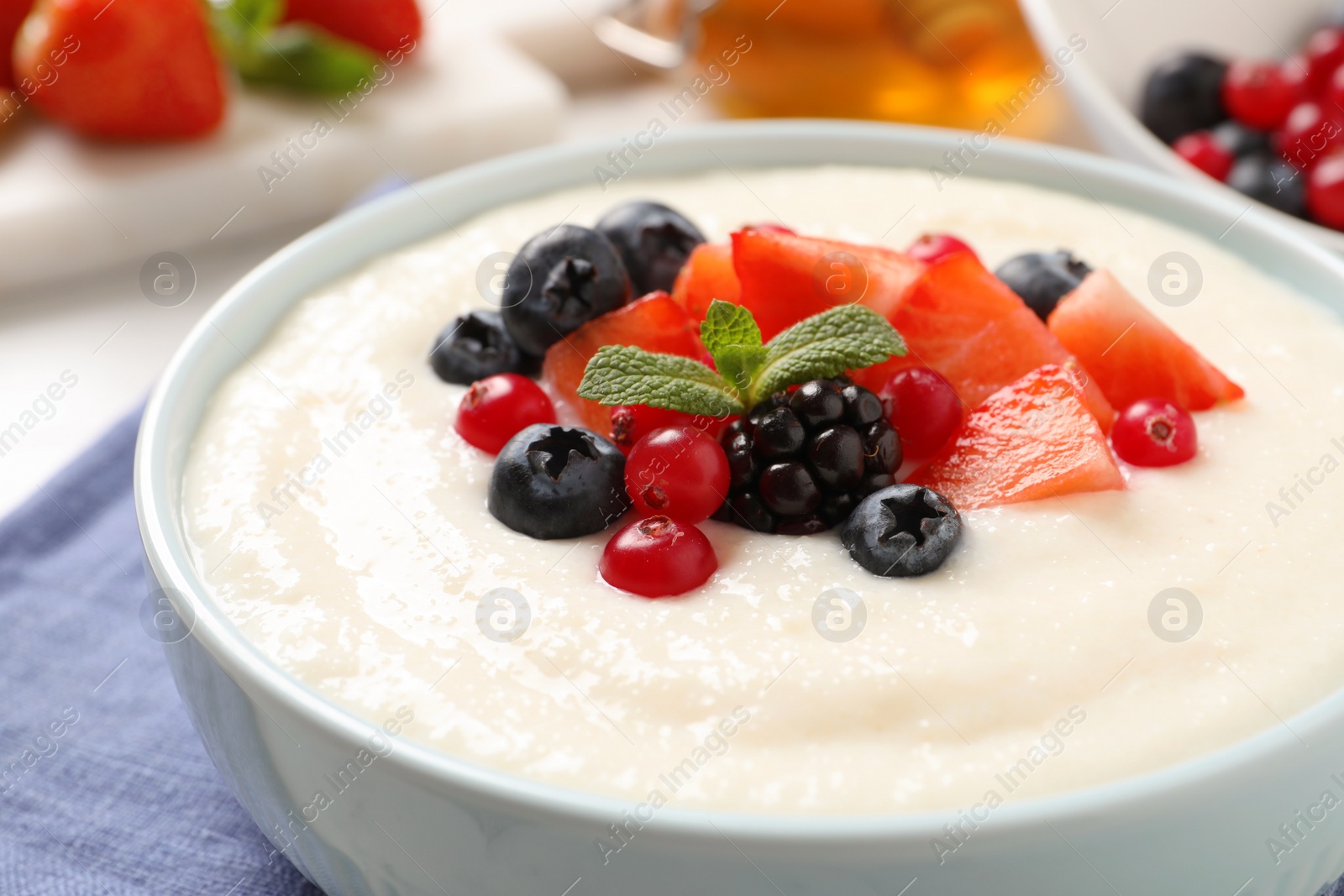 Photo of Delicious semolina pudding with berries in bowl on table, closeup