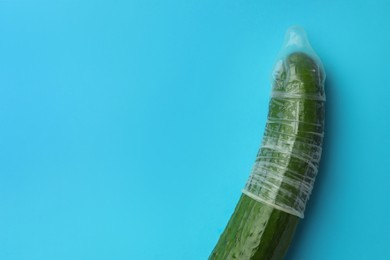 Photo of Cucumber with condom on light blue background, top view and space for text. Safe sex concept