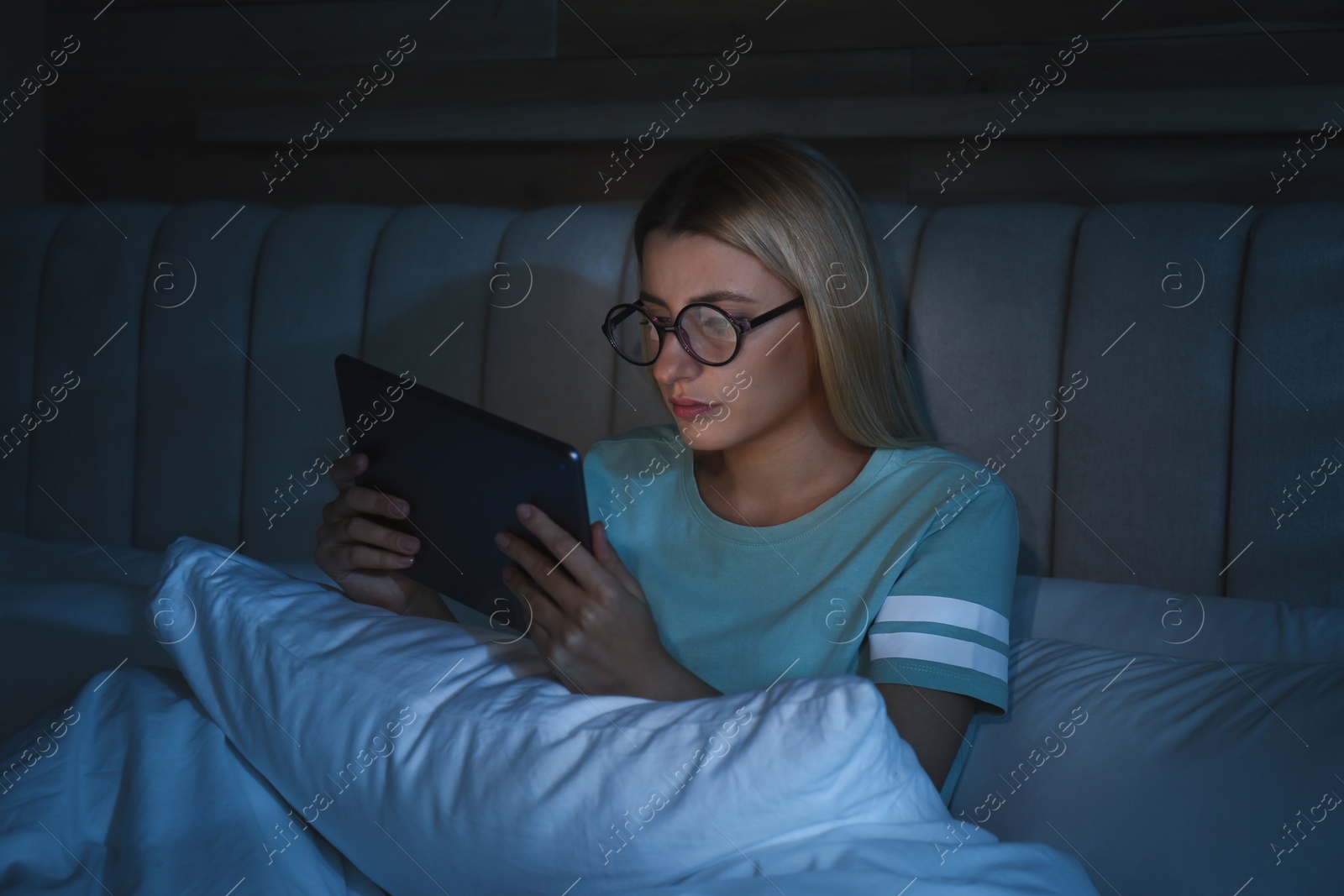 Photo of Young woman using tablet in bed at night. Sleeping disorder problem