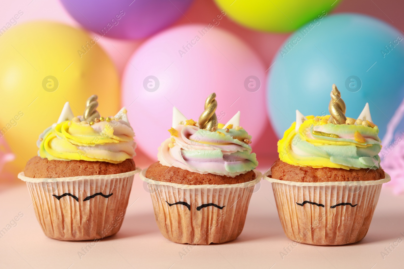 Photo of Cute sweet unicorn cupcakes on beige table