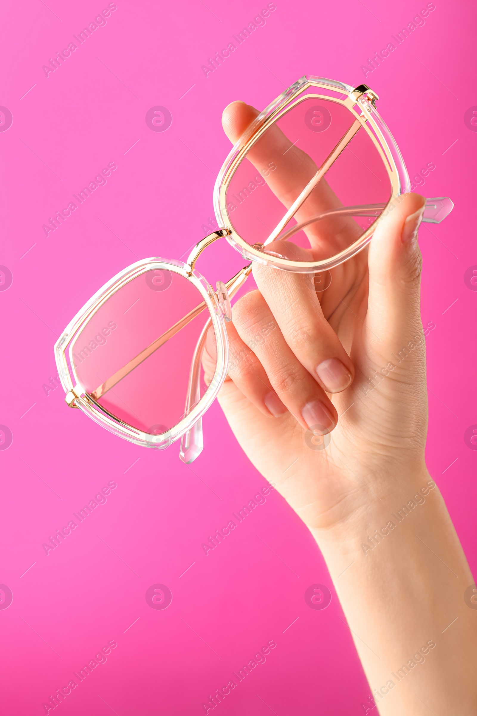 Photo of Woman holding stylish sunglasses on pink background, closeup of hand