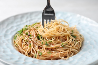 Photo of Tasty cooked noodles with fork on plate, closeup