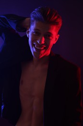 Photo of Sexy young man on dark background in neon lights