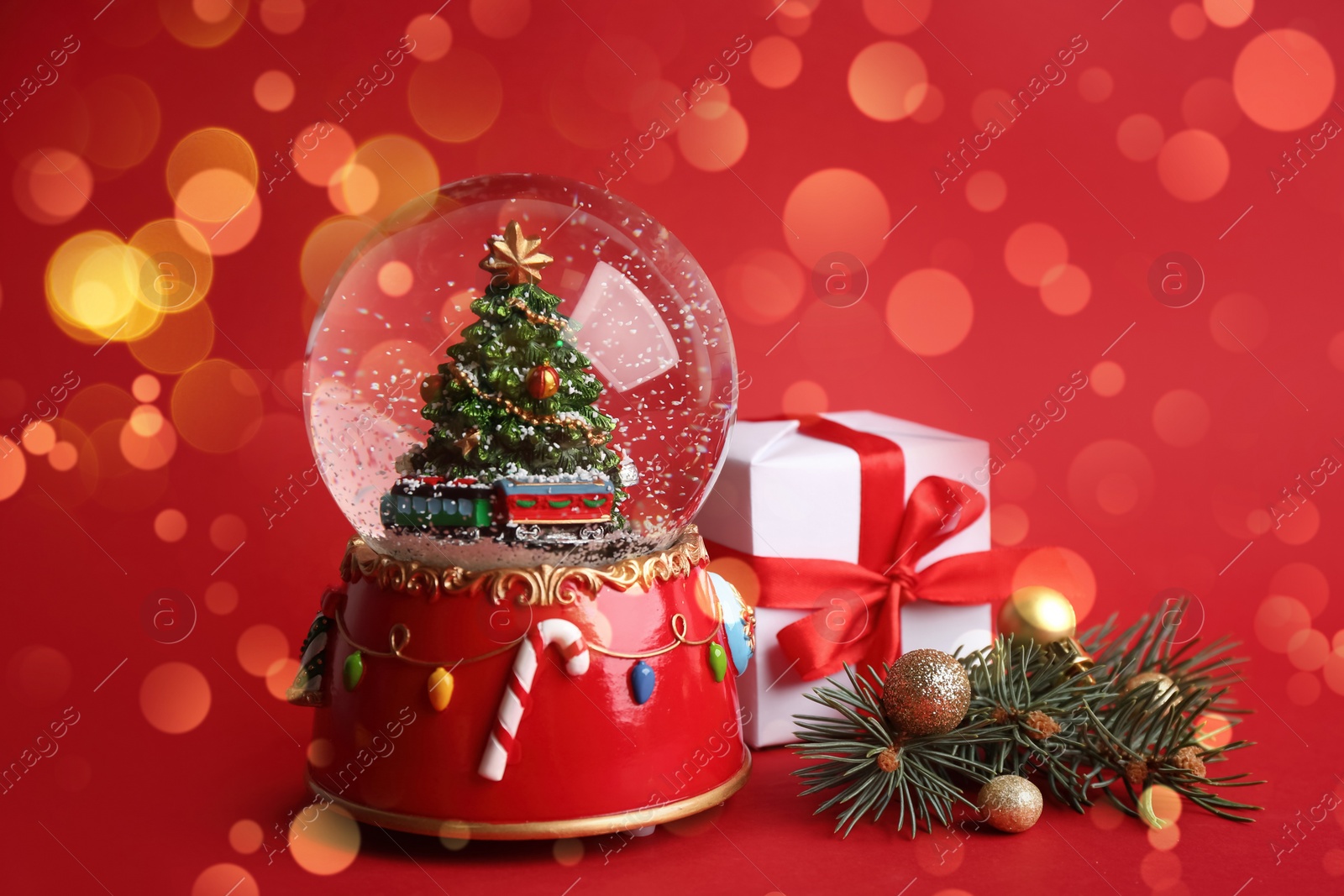 Image of Beautiful snow globe and Christmas decor on red background. Bokeh effect