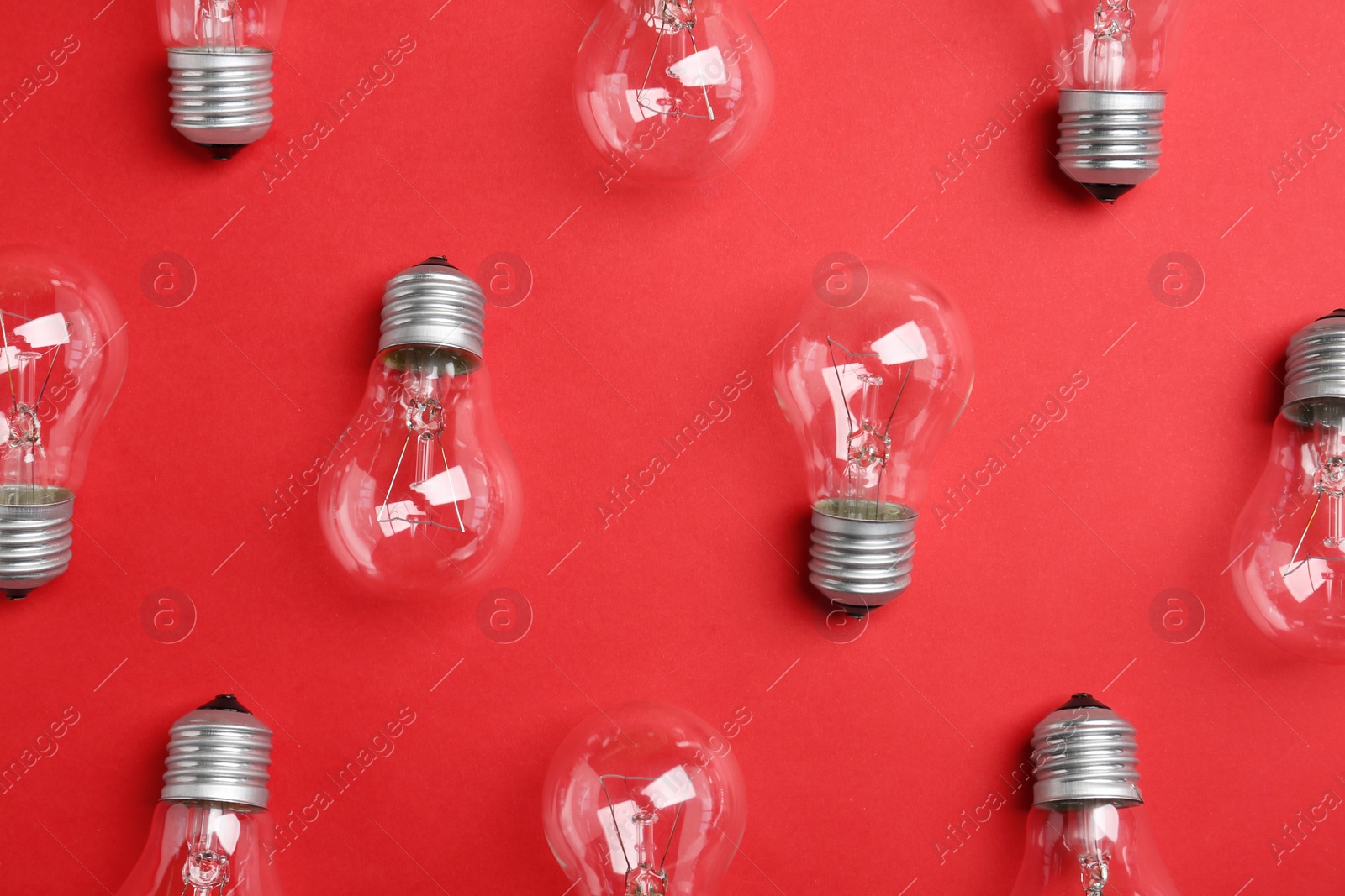 Photo of New incandescent lamp bulbs on red background, flat lay