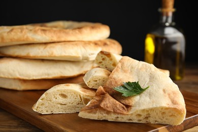 Cut fresh pita bread on wooden table, closeup