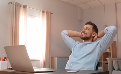 Young man working with laptop at desk in home office