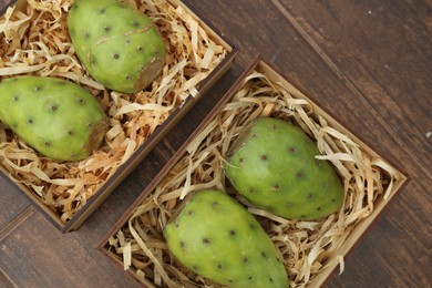 Delicious fresh ripe opuntia fruits in boxes on wooden table, flat lay