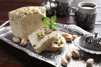 Photo of Tasty halva with pistachios and mint served on wooden table, closeup