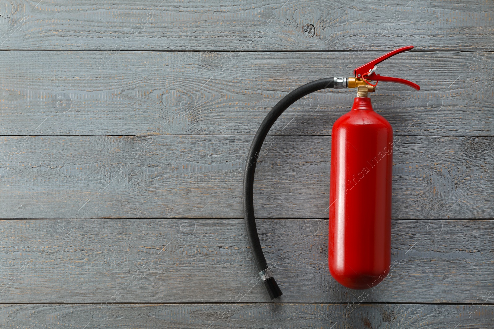 Photo of Fire extinguisher on grey wooden background, top view. Space for text