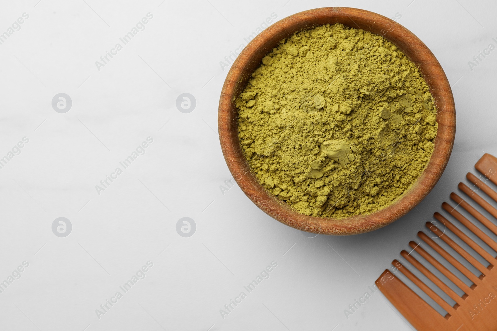 Photo of Bowl of henna powder and comb on white marble table, flat lay. Space for text