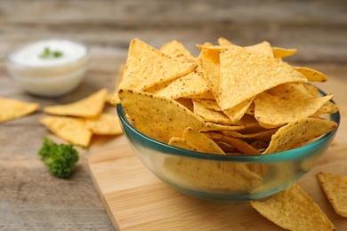 Photo of Bowl of Mexican nacho chips on wooden table, closeup