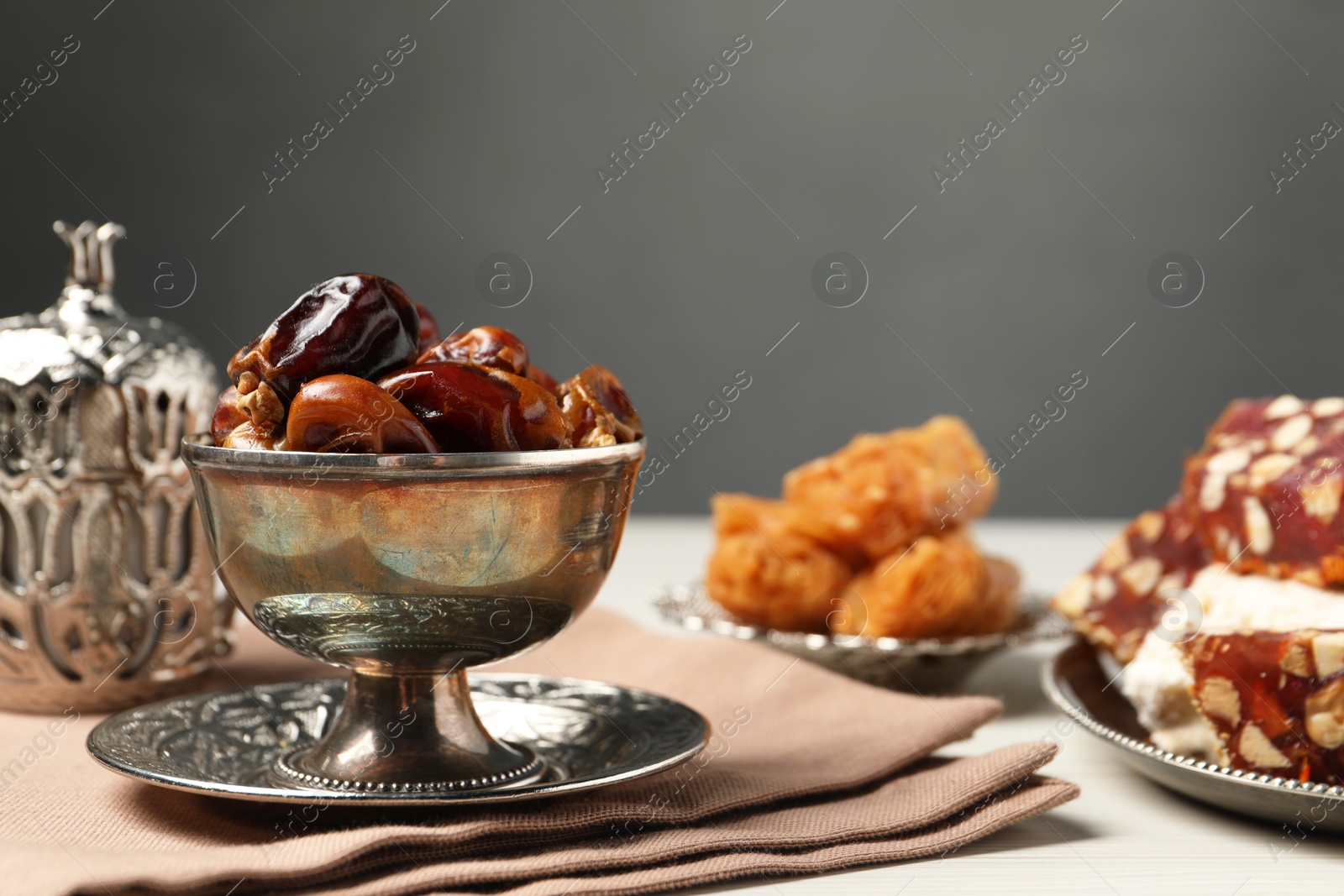 Photo of Date fruits, Turkish delight and baklava dessert served in vintage tea set on white table, space for text