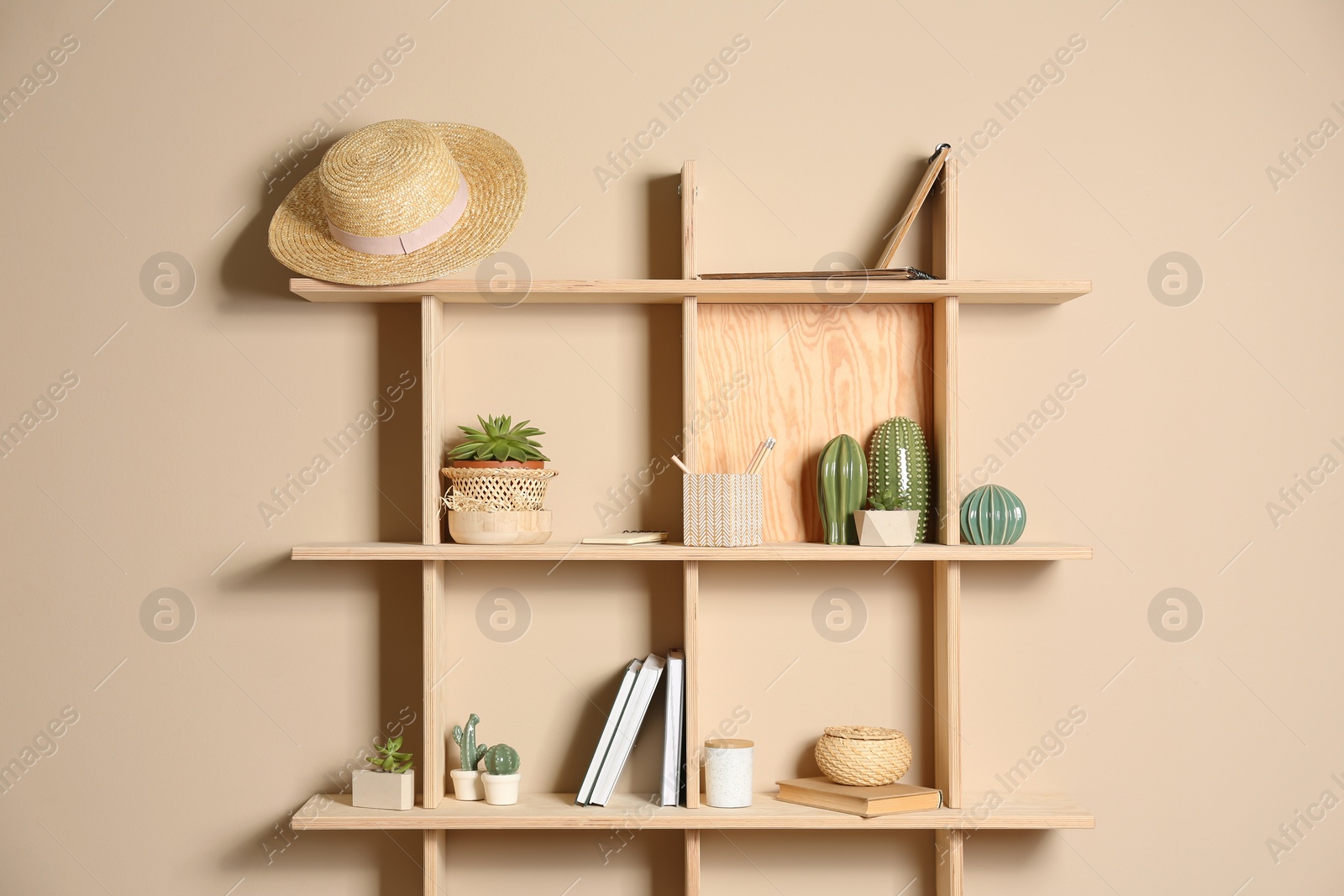 Photo of Wooden shelves with different decorative elements on beige wall