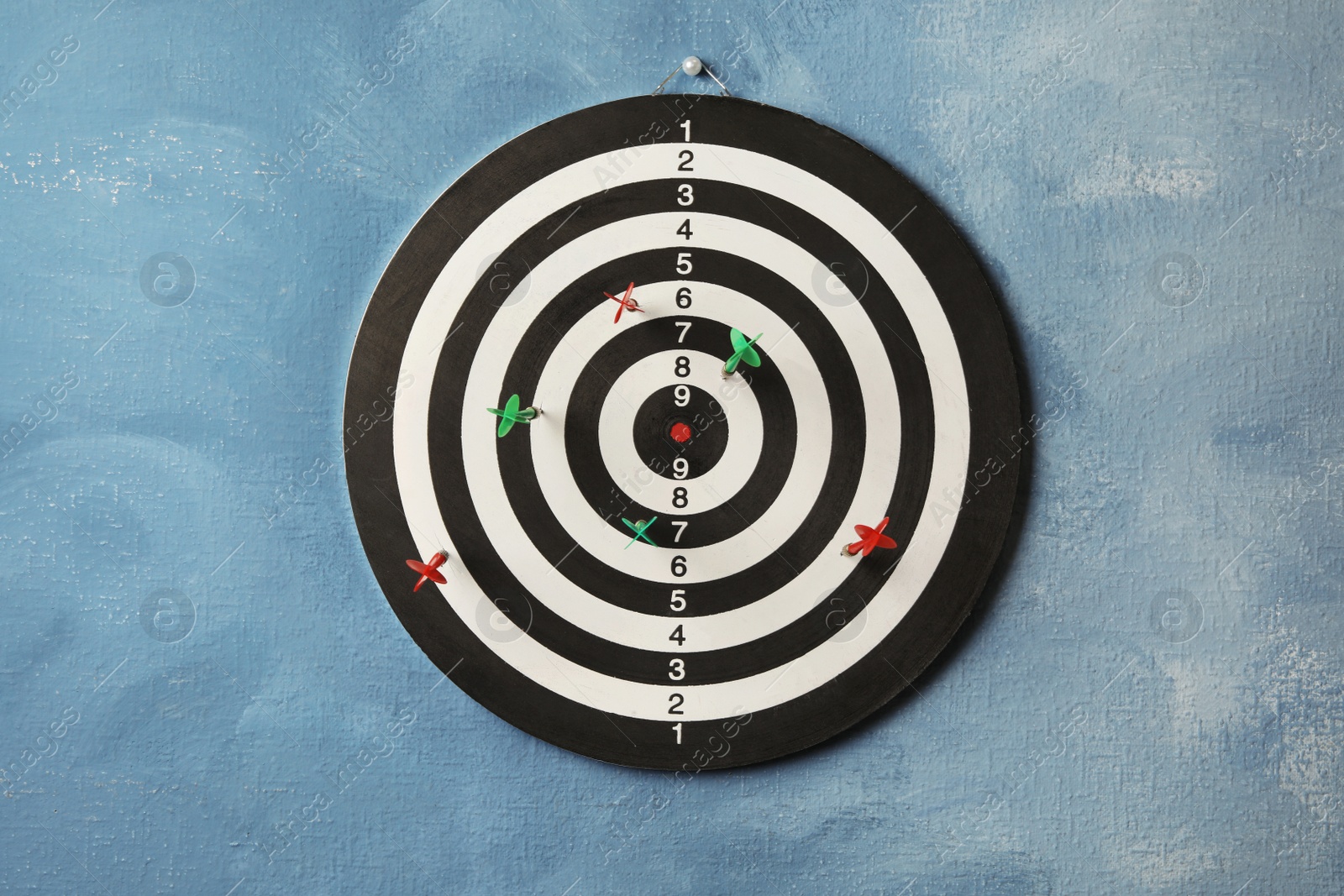 Photo of Arrows hitting dart board on blue wall