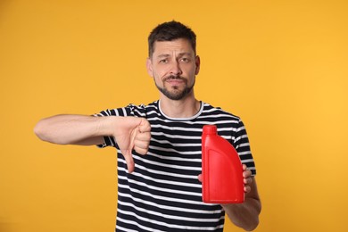 Photo of Man holding red container of motor oil and showing thumbs down on orange background