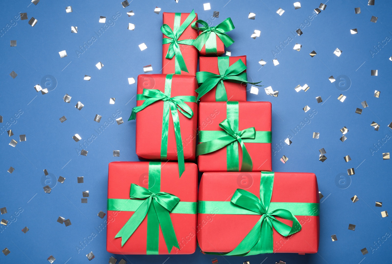 Photo of Christmas tree made with different gift boxes on blue background, flat lay