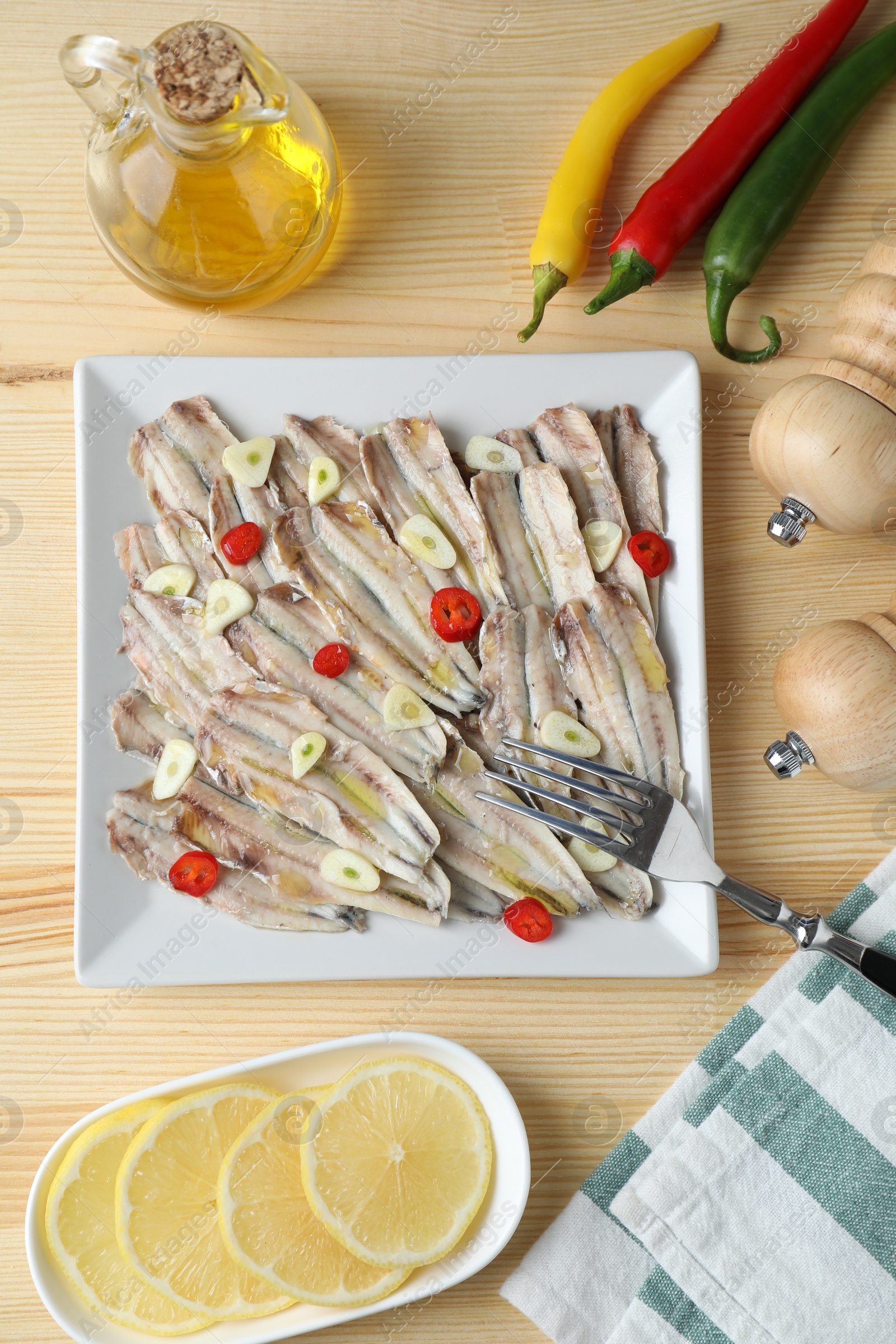 Photo of Tasty pickled anchovies served on wooden table, flat lay