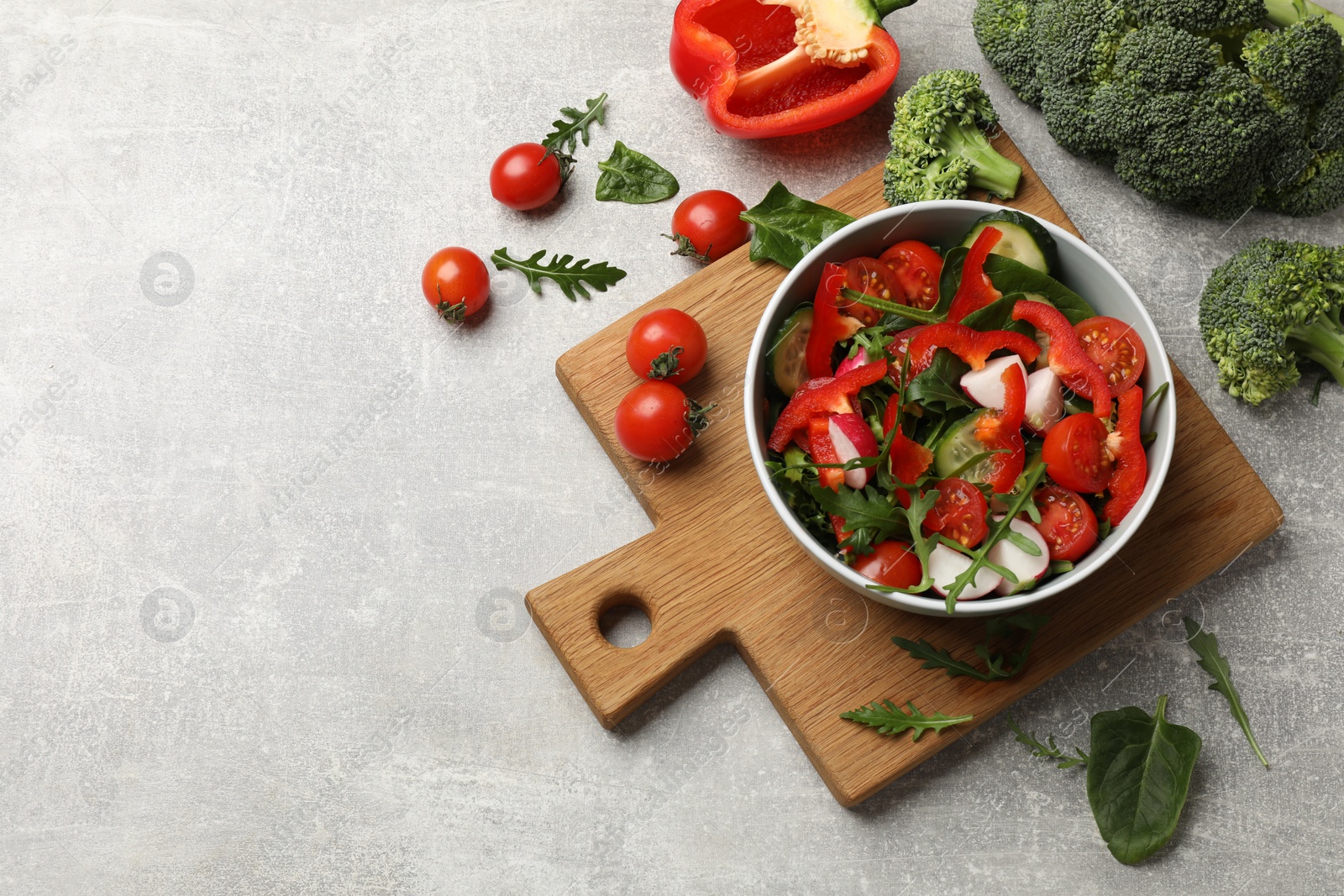 Photo of Tasty fresh vegetarian salad on light grey table, flat lay. Space for text