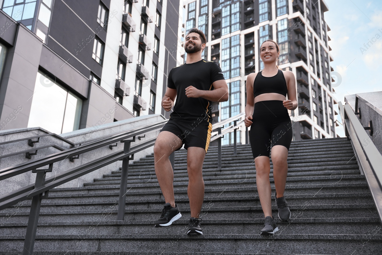 Photo of Healthy lifestyle. Happy couple running on steps outdoors, low angle view