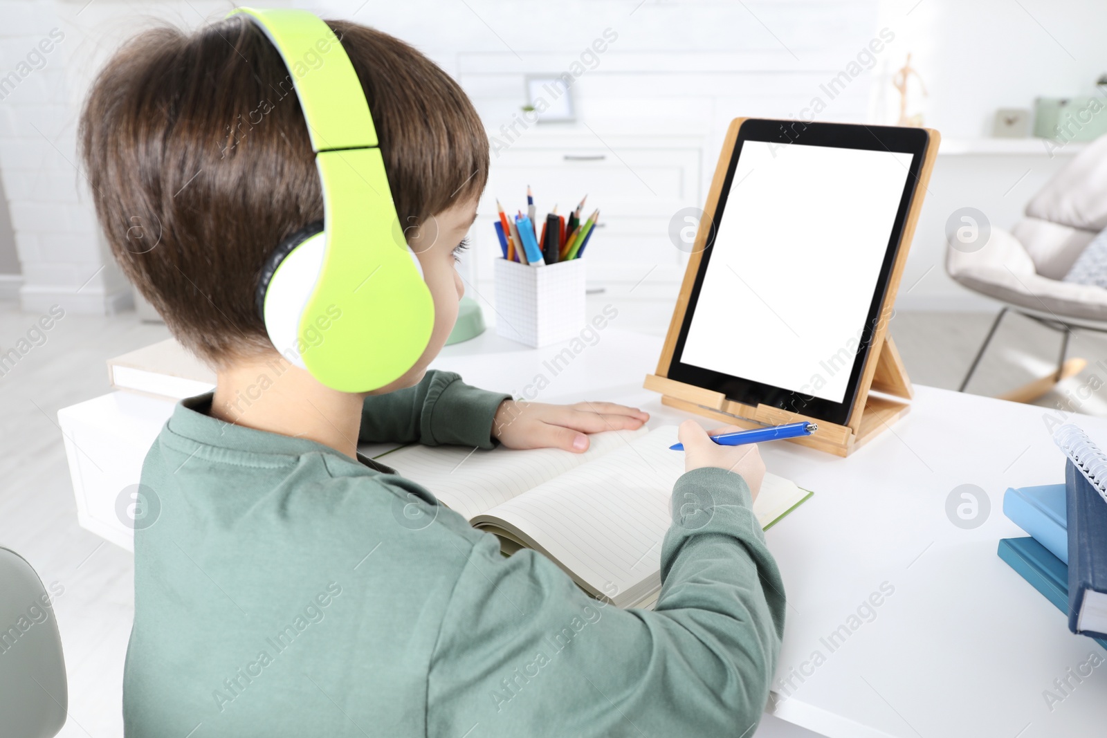Photo of Cute little boy with modern tablet studying online at home. E-learning