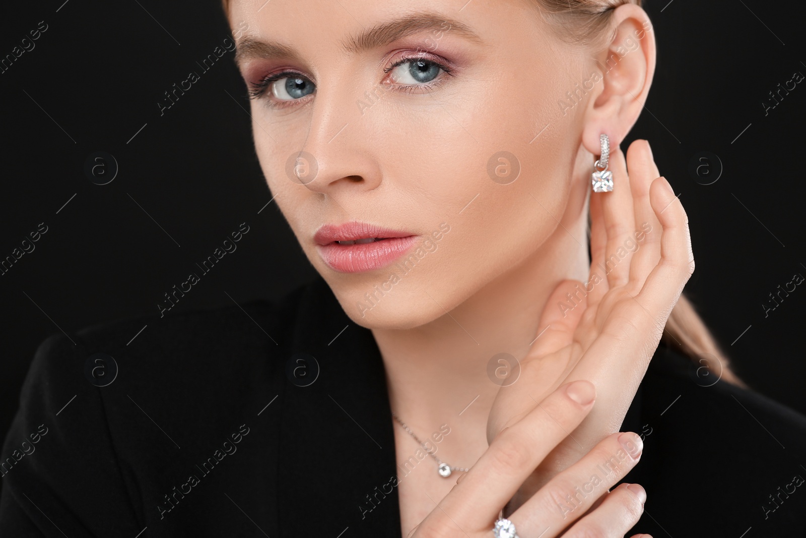 Photo of Beautiful young woman with elegant jewelry on black background, closeup