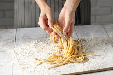 Photo of Woman with homemade pasta at light tiled table, closeup