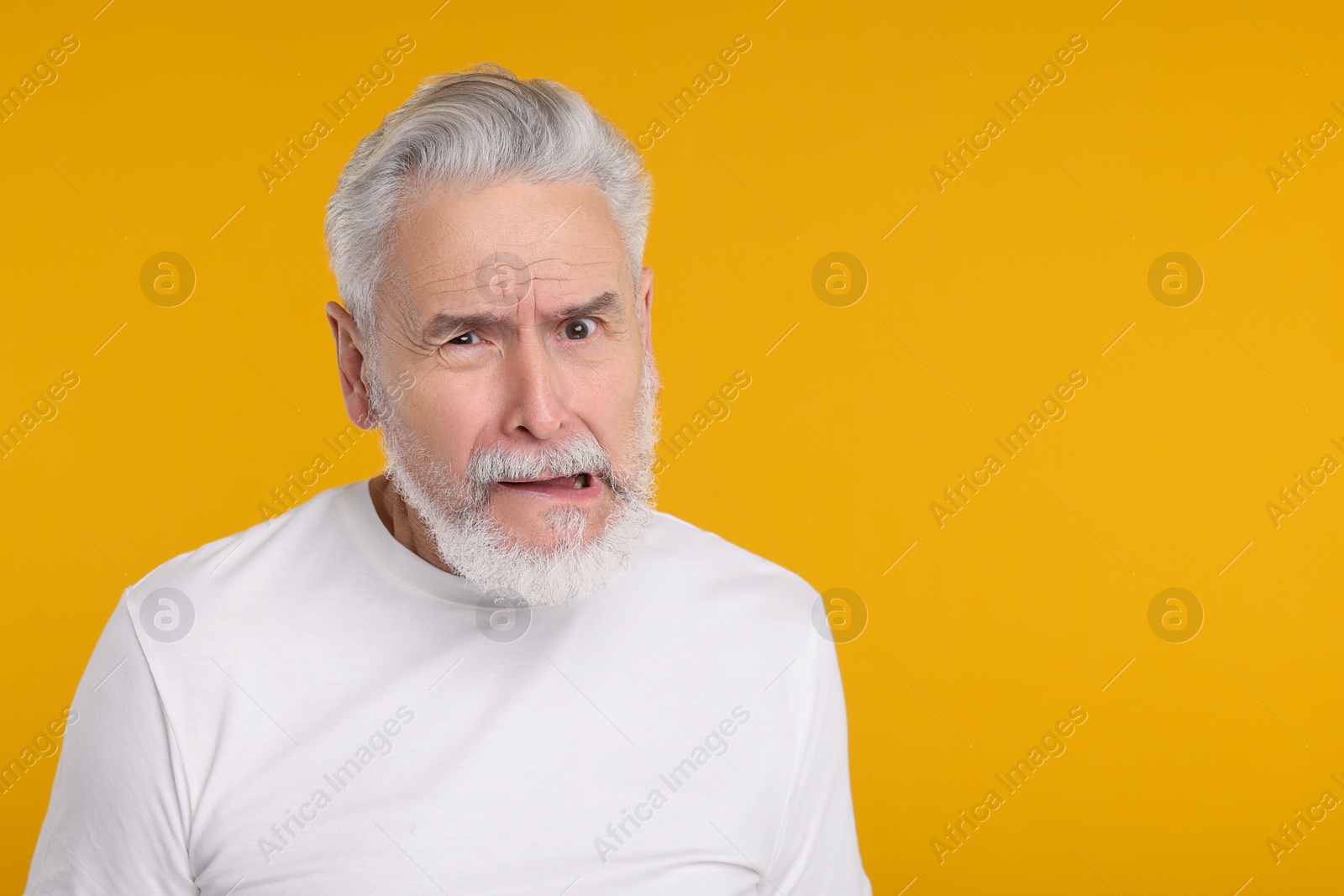 Photo of Portrait of surprised senior man on yellow background, space for text