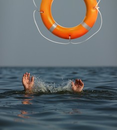 Drowning man with raised hands getting lifebelt in sea