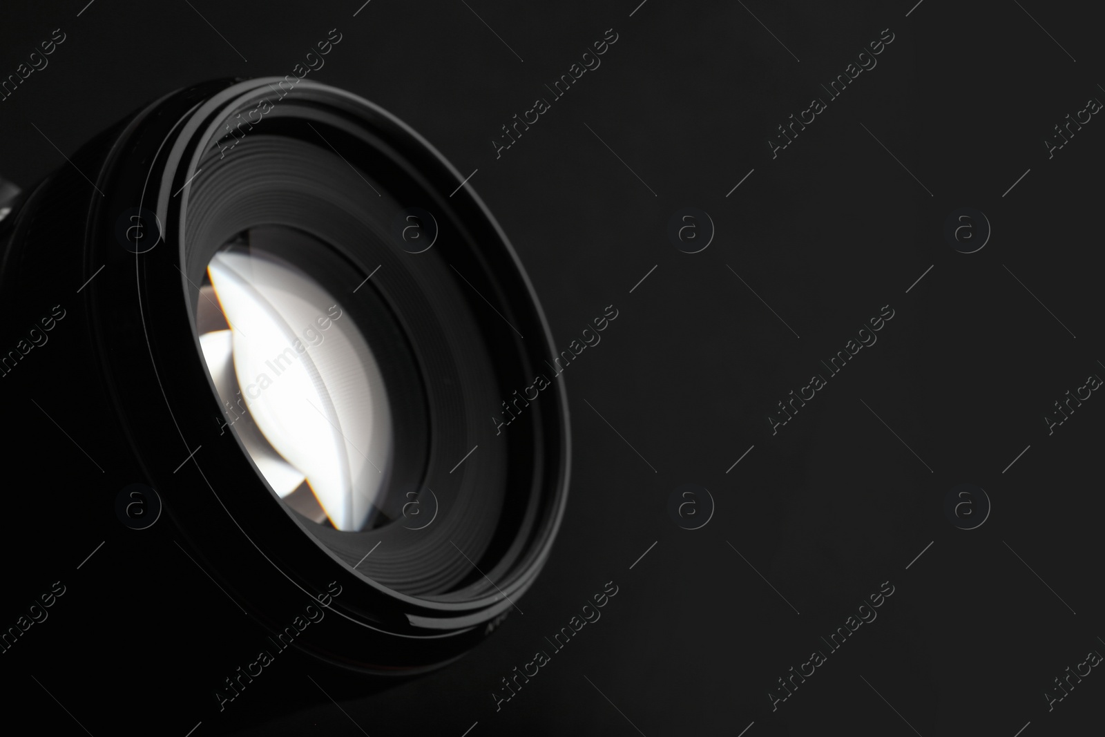 Photo of Modern camera lens on black background, closeup. Space for text