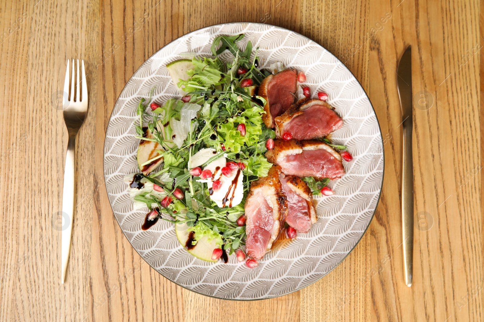 Photo of Delicious salad with roasted duck breast served on wooden table, flat lay