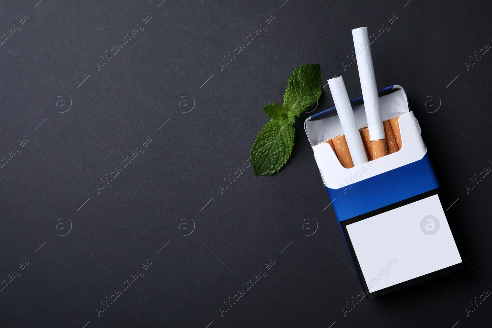 Photo of Pack of menthol cigarettes and mint on black background, flat lay. Space for text