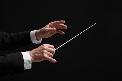 Professional conductor with baton on black background, closeup