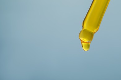 Photo of Dripping yellow serum from pipette on grey background, closeup. Space for text