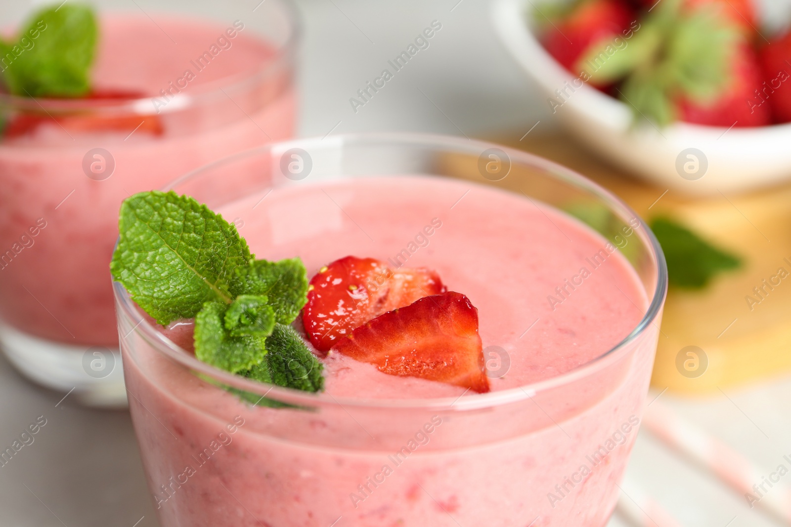 Photo of Tasty strawberry smoothie with mint in glass on table, closeup