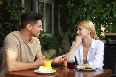 Photo of Young woman having boring date with talkative man in outdoor cafe