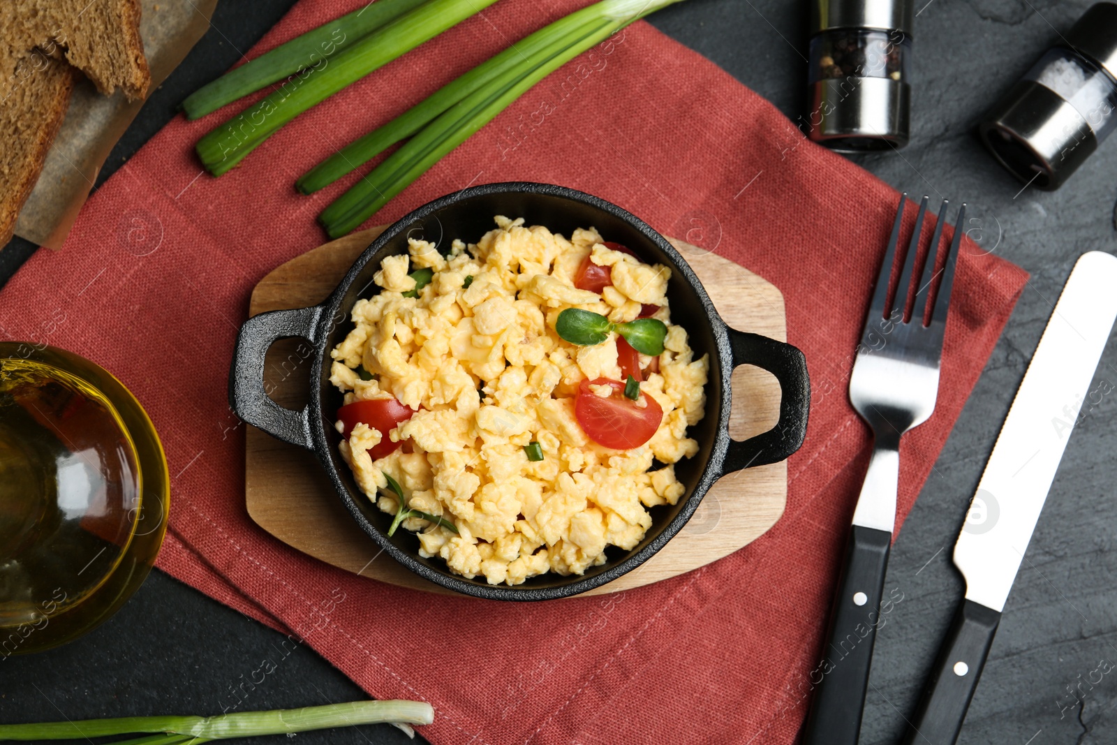 Photo of Tasty scrambled eggs served on black table, flat lay