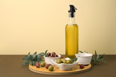 Photo of Oil, olives and tree twigs on brown table