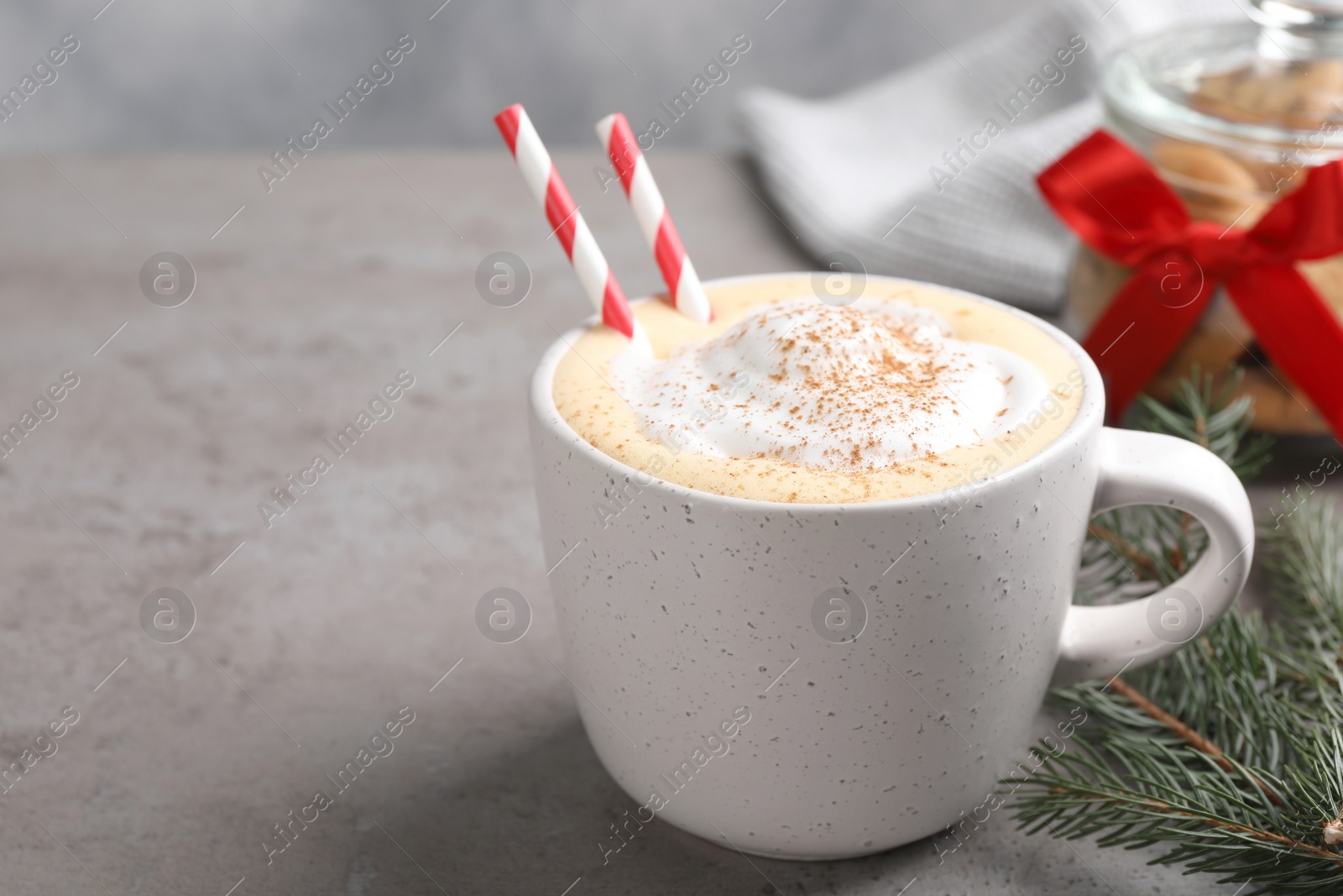 Photo of Cup of delicious eggnog with cinnamon on gray table, space for text