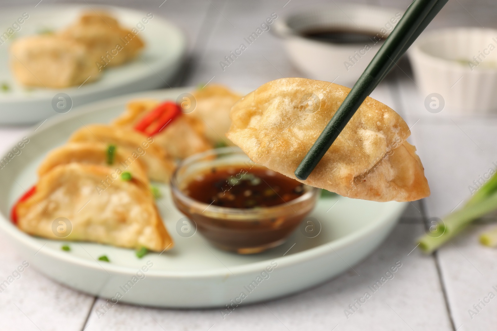 Photo of Taking delicious gyoza (asian dumpling) from plate at table, closeup. Space for text