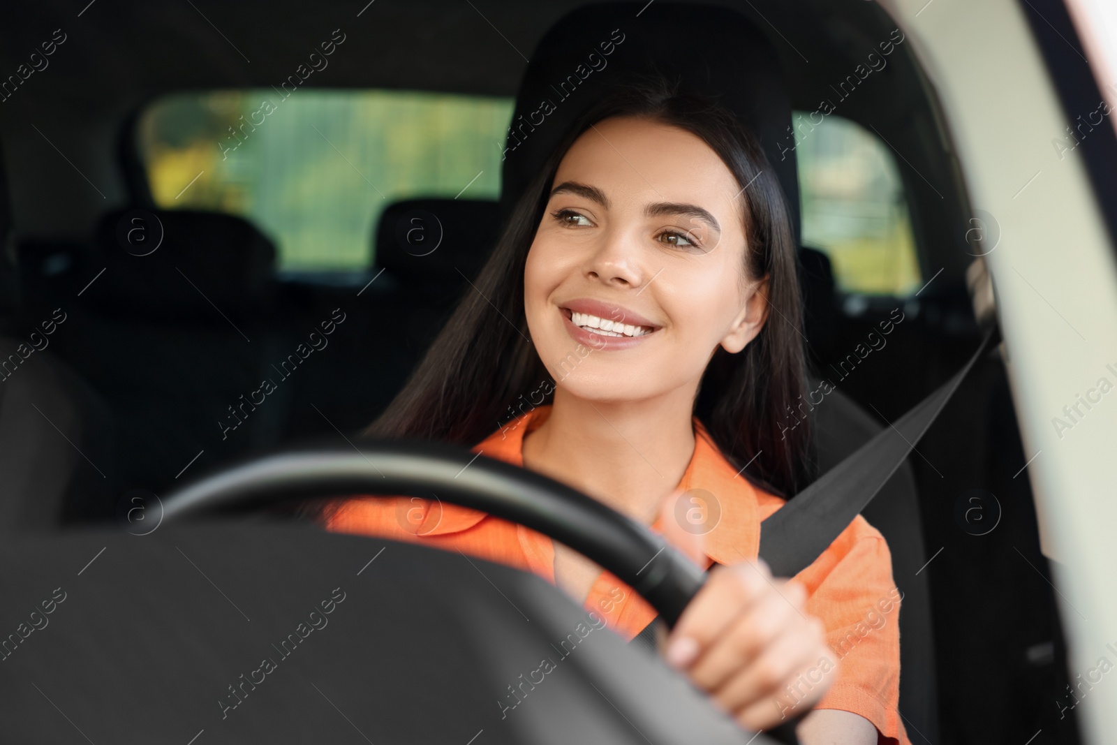 Photo of Enjoying trip. Happy young woman driving her car, view through windshield