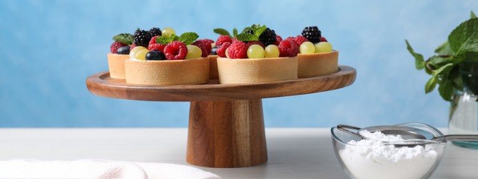 Image of Delicious tartlets with berries on white table. Banner design