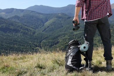 Photo of Back view of tourist with hiking equipment and binoculars in mountains, closeup