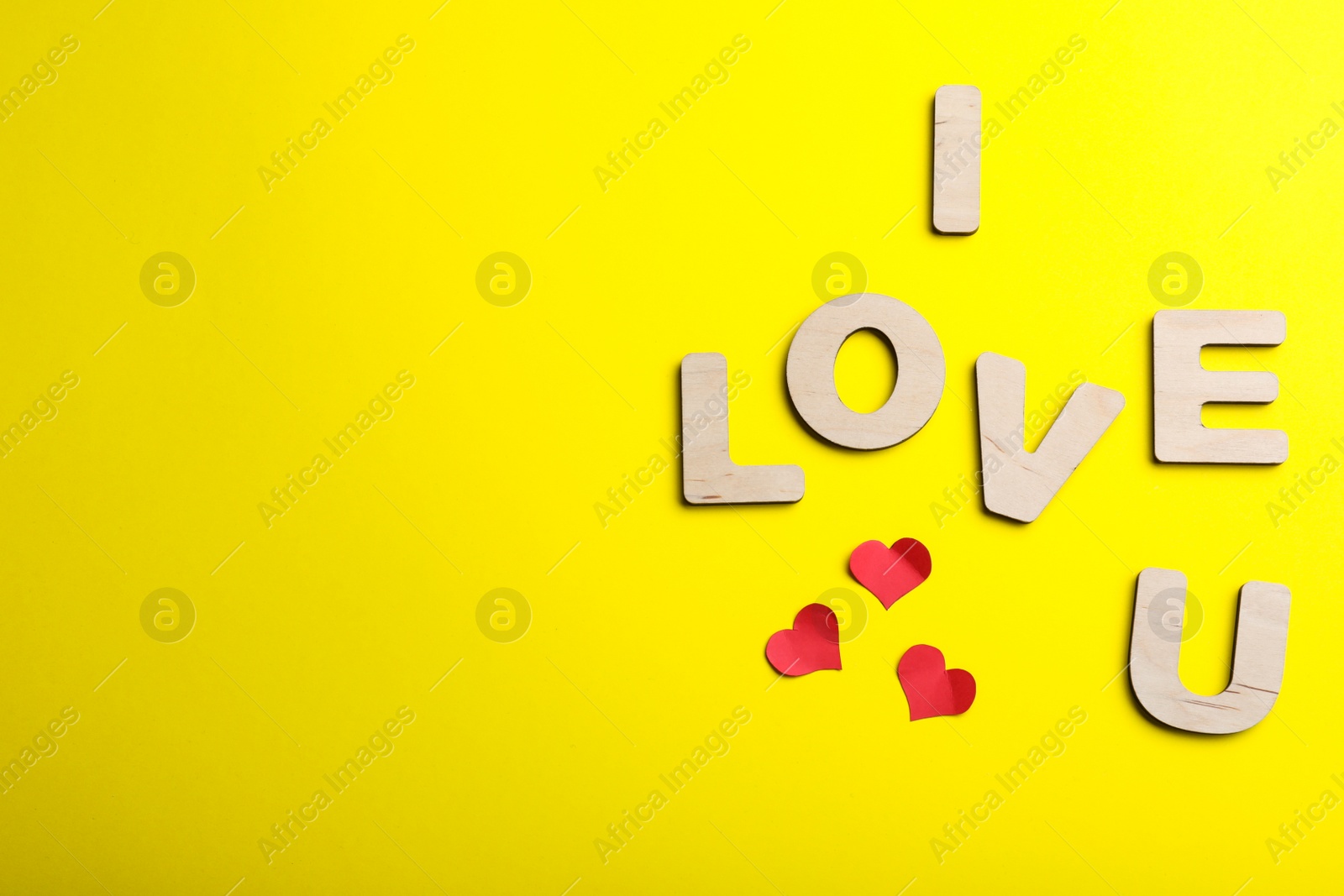 Photo of Phrase I Love You made of wooden letters on yellow background, flat lay. Space for text