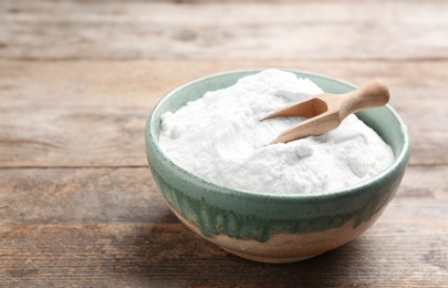 Photo of Bowl with baking soda and scoop on wooden table