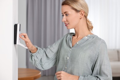 Photo of Woman entering code on home security system in room