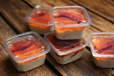 Photo of Savoury spread with lard in plastic containers on wooden table. Food delivery service