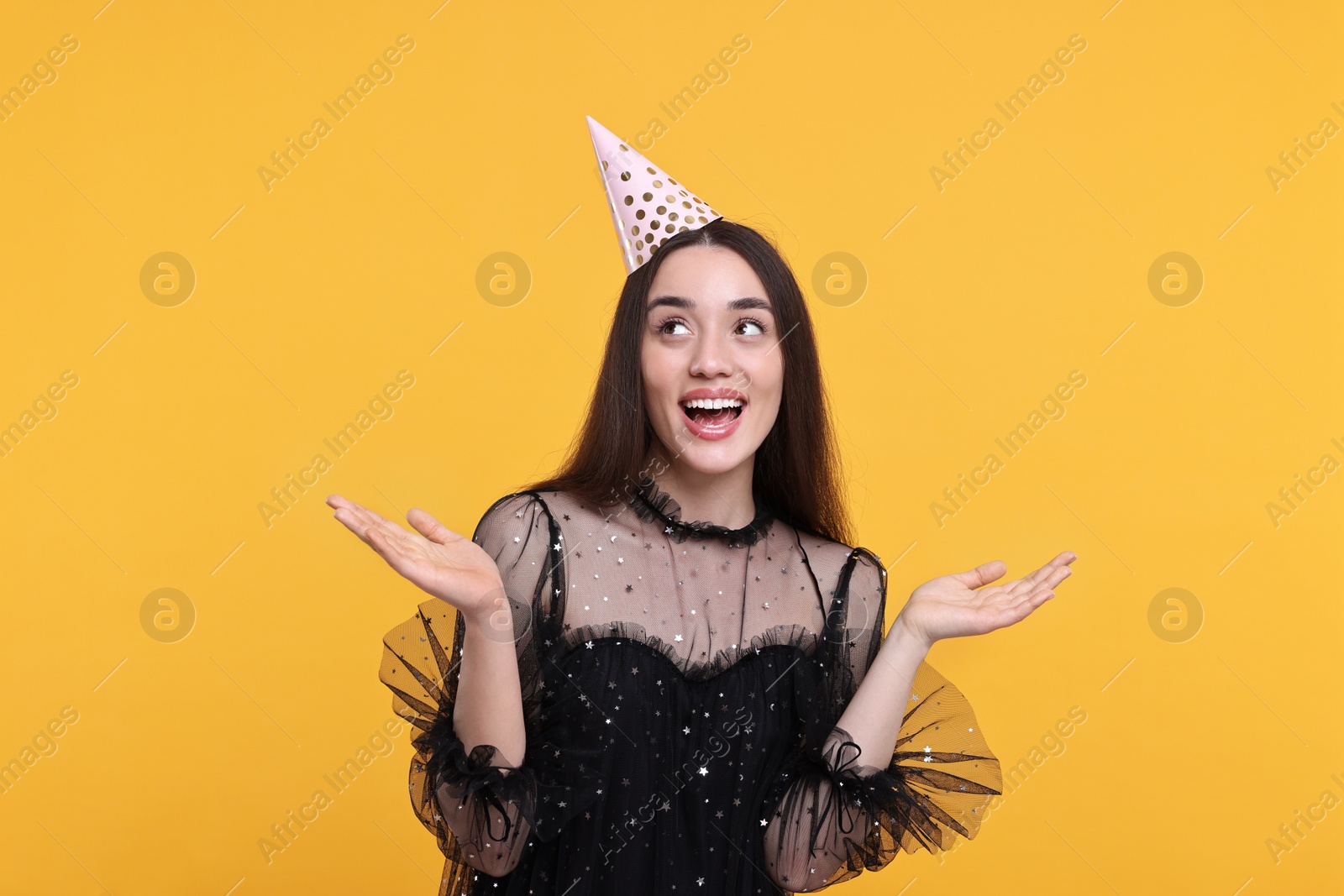 Photo of Happy woman in party hat on orange background