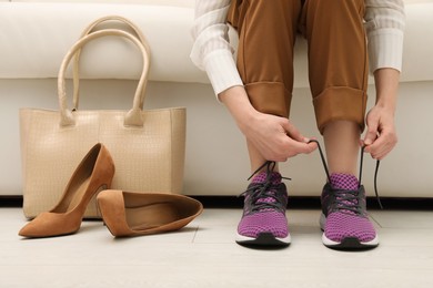 Photo of Woman changing shoes on sofa in office, closeup